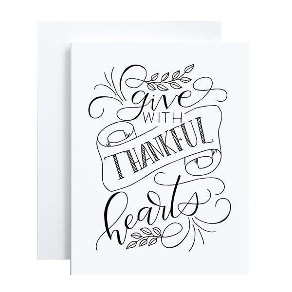 Give with thankful hearts hand lettered greeting card design in black on a folded white card with A2 envelope