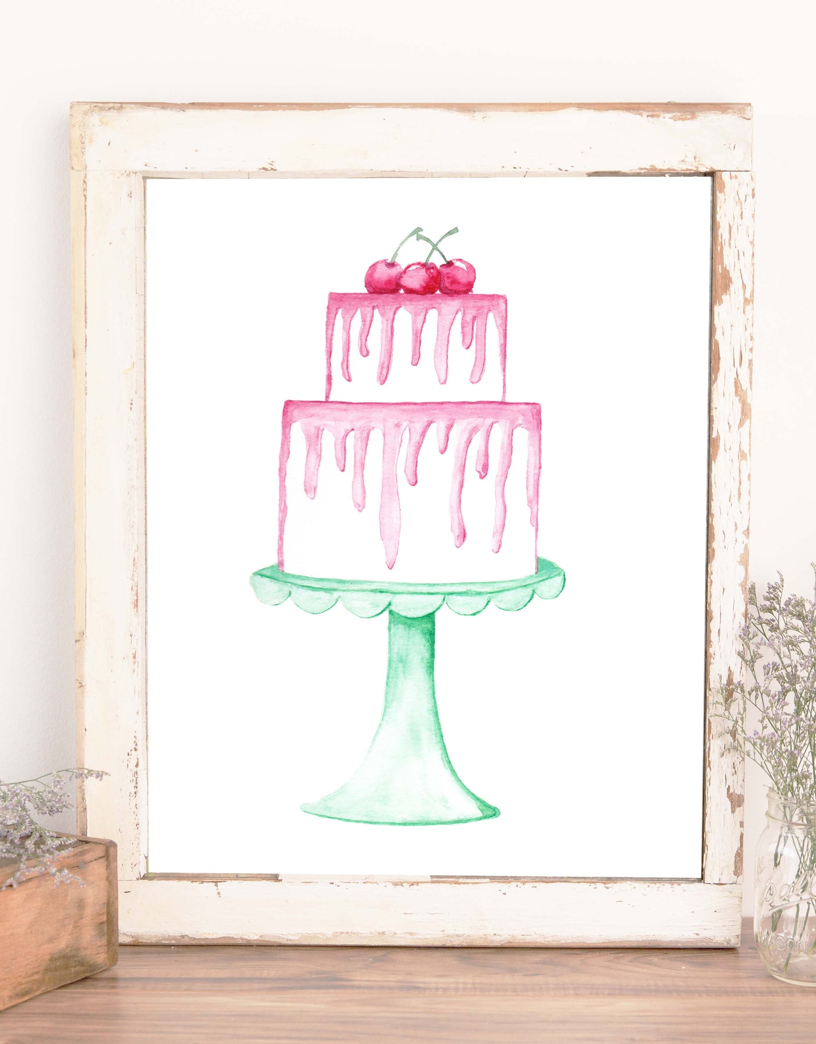 watercolor painted layered white cake with dripping pink frosting topped with three red cherries and sitting on a seafoam green scalloped cake stand