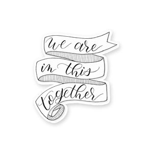 3" hand lettered, illustrated, black and white vinyl sticker that says we are in this together with a ribbon banner illustration