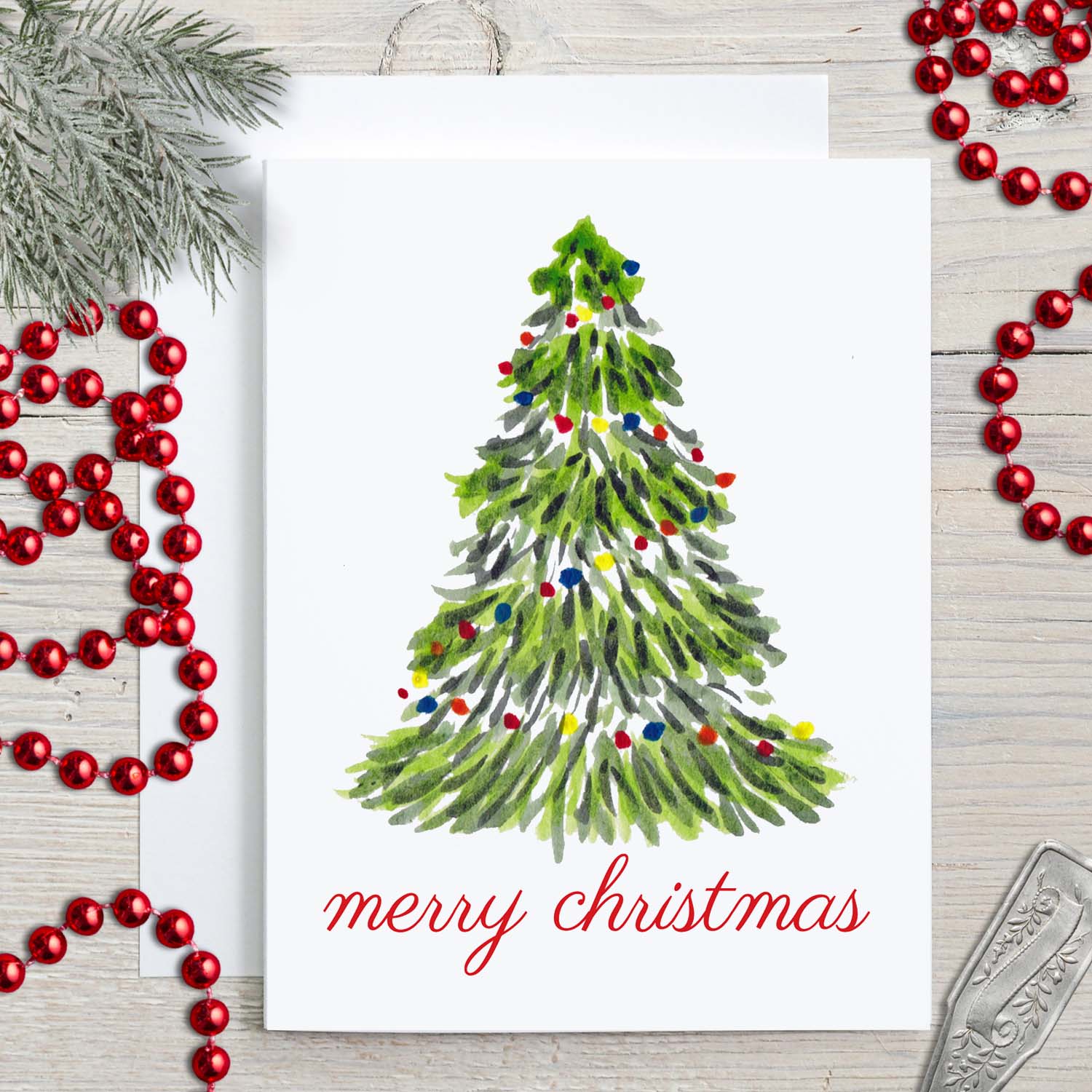 Merry Christmas greeting card with a watercolor Christmas tree with colorful lights and merry christmas message shown with christmas decor