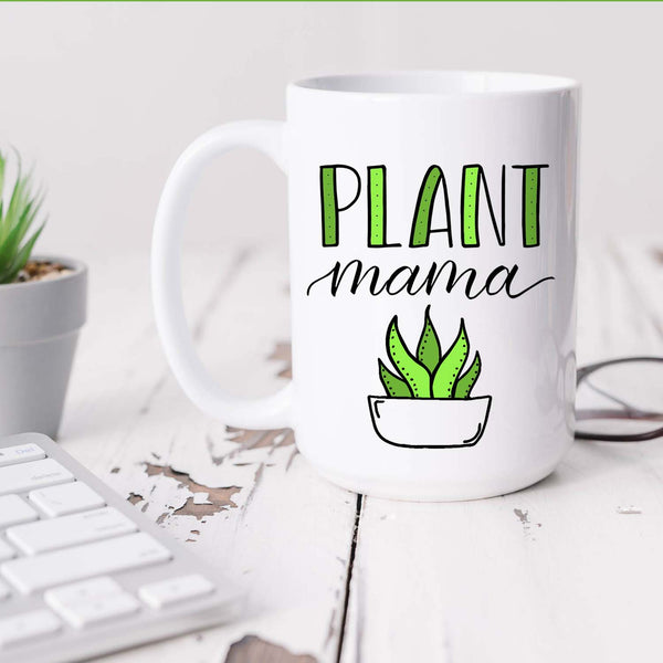 15oz white ceramic mug with hand lettered illustrated design that says Plant mama with the illustration of a succulent with green leaves shown sitting on a white office desk