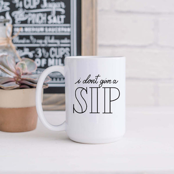 15oz white ceramic mug with hand lettered illustrated design that says I don't give a sip shown sitting in a kitchen