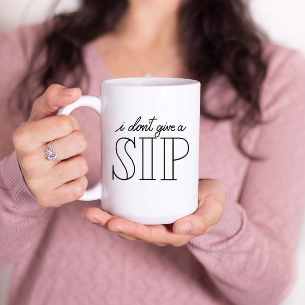 15oz white ceramic mug with hand lettered illustrated design that says I don't give a sip shown with a woman holding the mug